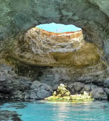 Interior of Otranto sea cave with natural skylight and turquoise water along Puglia coastline