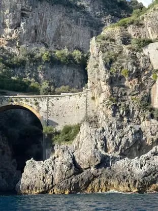 Fiordo di Furore stone bridge and vertical limestone cliffs seen from water level