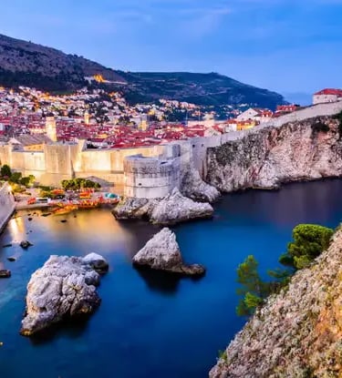 Dubrovnik old town walls and harbor illuminated at dusk, Croatia