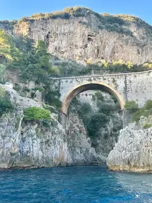 Historic stone arch bridge between dramatic limestone cliffs on the Amalfi Coast