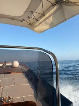 Traditional Gozzo boat with shade canopy cruising on open Mediterranean Sea along Amalfi Coast