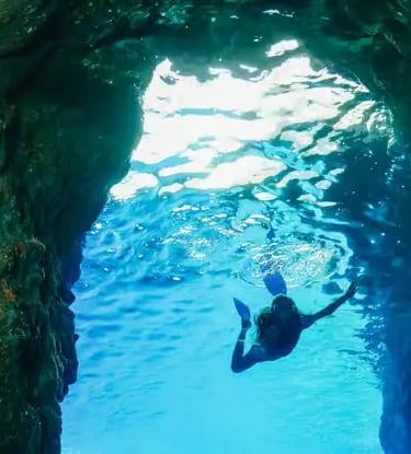 Snorkeler swimming through an underwater cave in crystal-clear Amalfi Coast waters
