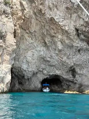 Narrow Blue Grotto cave entrance in Capri with small wooden boat waiting on turquoise water