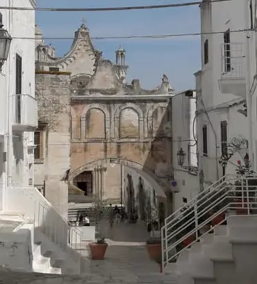 Whitewashed alley with baroque church and stone staircase in Ostuni, the White City of Puglia