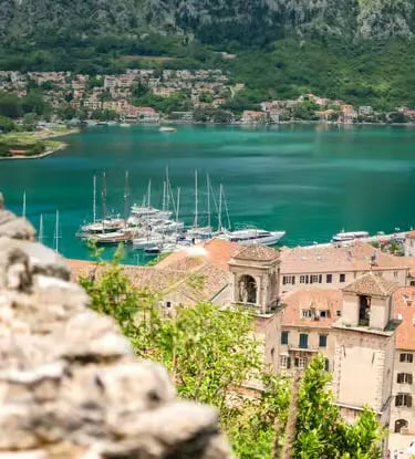  Elevated view of Kotor old town and turquoise Bay of Kotor with yachts and green mountains
