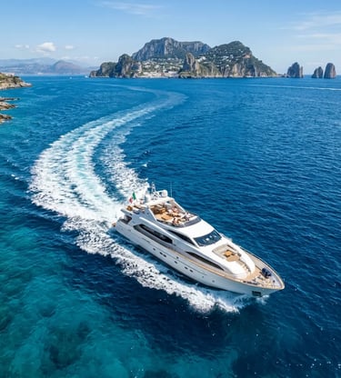Aerial view of private yacht cutting through blue Tyrrhenian Sea toward Capri and Faraglioni