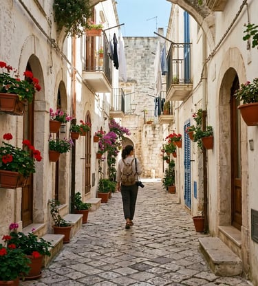 Traveler walking cobblestone alley in Monopoli old town with flower pots Puglia Italy