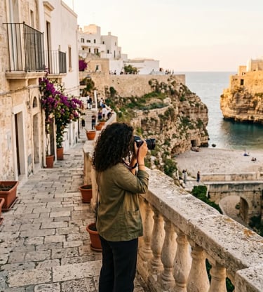 Woman with DSLR camera photographing Polignano a Mare cliffs and Lama Monachile beach from balcony