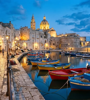 Colorful fishing boats in Monopoli Porto Vecchio harbor with cathedral dome at blue hour, Puglia