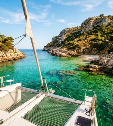 Luxury catamaran anchored in a turquoise cove with limestone cliffs in Menorca