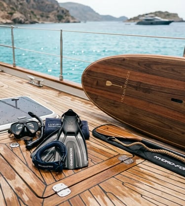 Professional snorkeling gear and wooden paddleboard arranged on polished teak yacht deck