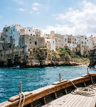 View of Polignano a Mare white cliffs from a wooden sailing boat deck