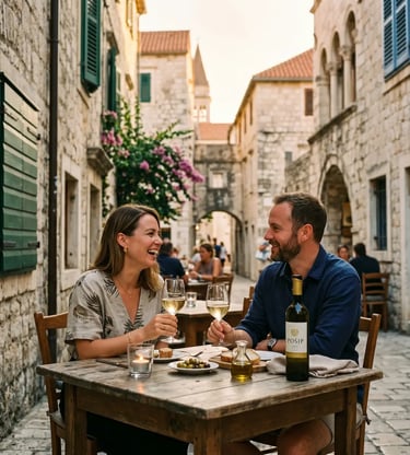 Couple laughing over Pošip wine at outdoor table in Trogir old town stone alley