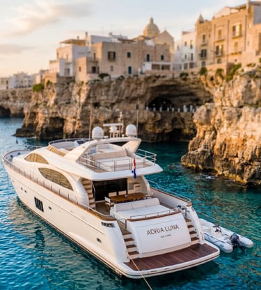 Luxury private charter yacht anchored in turquoise Adriatic water beneath Polignano a Mare cliffs