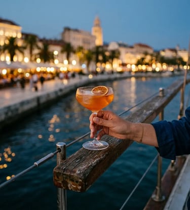 Hand holding cocktail on sailboat railing with Split Riva promenade lights at dusk