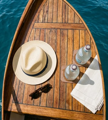 Wooden Caprese gozzo deck with straw hat, chilled drinks and linen towel over turquoise sea