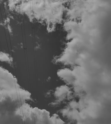 Cielo nublado en blanco y negro con cables de alta tensión. Fotografía urbana minimalista.