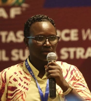 a woman in a yellow shirt and glasses speaking into a microphone