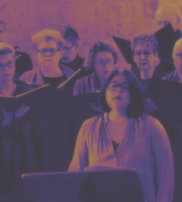 A community choir group performing a vocal concert with sheet music under purple and gold lighting.