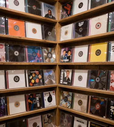 Stack of CDs showing both French and English versions side by side on a rustic wooden table.