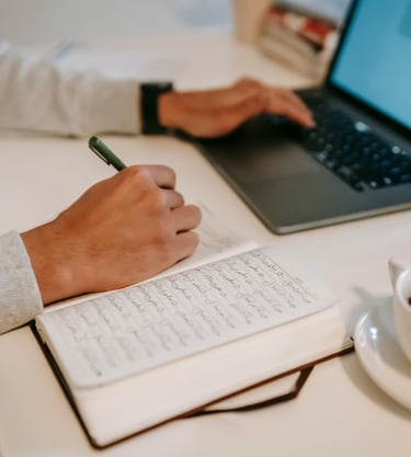 a person sitting at a desk with a pen and a cup of coffee