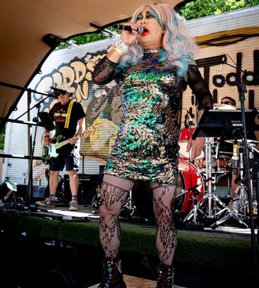 Magenta slipperz comedy drag ace singing at a festival
