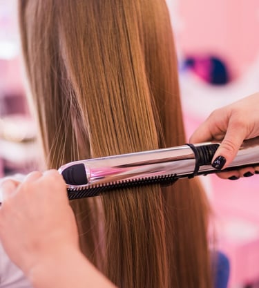 a woman is straightening her hair with a hair straightener