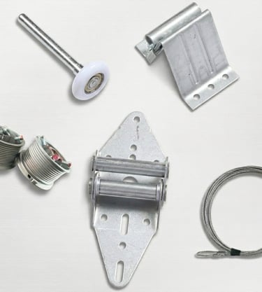 A collection of silver metal garage door replacement parts including rollers, hinges, cables, and drums.