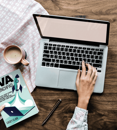a person sitting at a desk with a book and a cup of coffee
