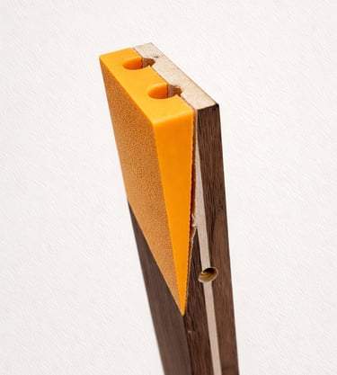 A textured orange door wedge mounted on a vertical dark wood board with holes.
