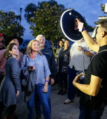 A group of friends posing for a photo with a portable ring light photo booth at an outdoor evening event.