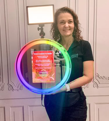 A woman holding a portable ring light photo booth with rainbow LED lighting for events.