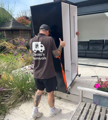a man in a black shirt is moving a refrigerator