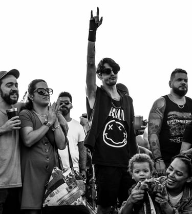 homem no publico fazendo dedos de rock em contraste com um publico familia e sorridente