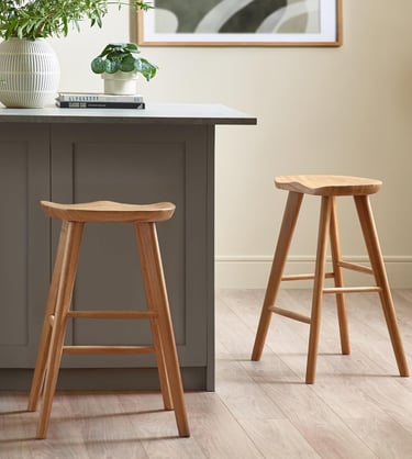 a kitchen counter with a wooden stool and a potted plant