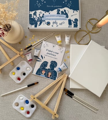 Kit créatif Paint Your Partner avec toiles, pinceaux, peintures et chevalets disposés sur une table.