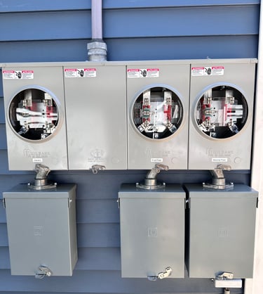 Milbank outdoor electrical meter sockets and disconnect boxes installed on blue siding.
