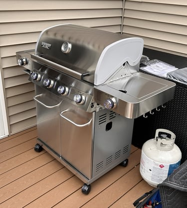 Left side view of stainless steel propane grill showing side burner and hooks