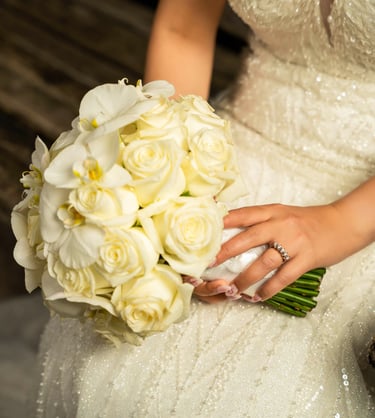 Bride holding a bouquet of white roses with her wedding ring visible, captures by Fred Art Studio
