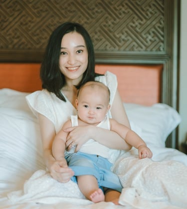 Mother holding baby on bed at Intercontinental Jimbaran in a calm and intimate family photography moment