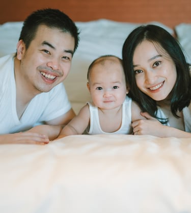Parents and baby lying together on bed at Intercontinental Jimbaran captured in a natural indoor family photography session