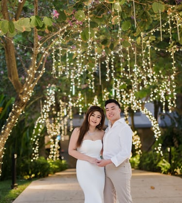 Couple standing under hanging garden lights during a romantic evening prewedding session at Apurva Kempinski Bali