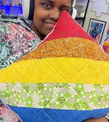 a woman holding a colorful pillow that has a rainbow - colored rainbow - colored pillow