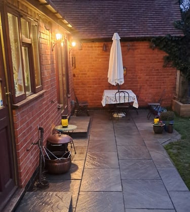 Illuminated backyard patio with grey slate flagstone tiles and a small outdoor dining table.