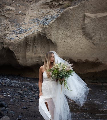 Bride standing on a serene Tenerife beach during a romantic wedding photoshoot.