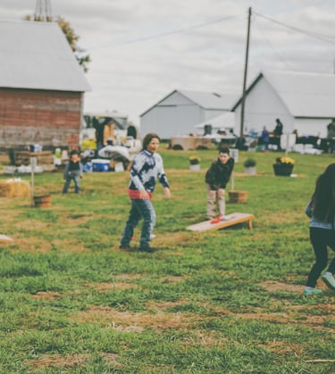 a group of children playing yard games in an open grassy field