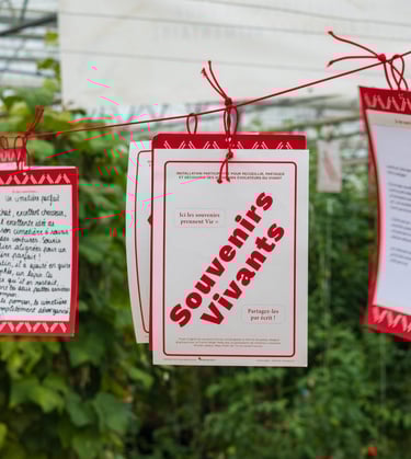 Une multitude de fiches de Souvenirs Vivants pendent au-dessus du sol, nouées à un fil rouge