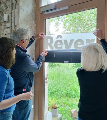 Perrine Rousselet et deux collaborateurs place le mot "Rêver" sur une porte vitrée