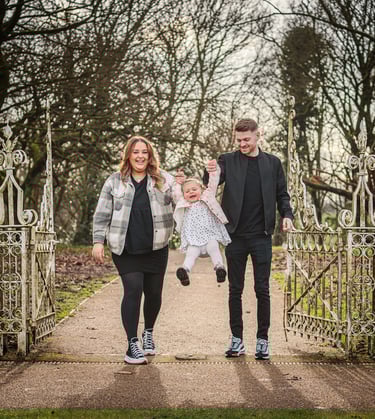 a man and woman holding a baby in a park