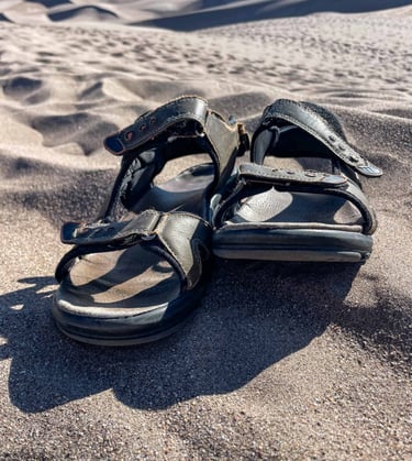 a pair of sandals that are on the sand
